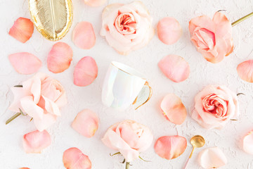 Stylish Cup of coffee, leaf golden plate and spoon with pink roses flowers and petals. Flatlay, top...
