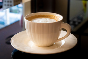 White cup of coffee, saucer on a black background.