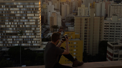 Photographer on top of a building registering the sunset in the city