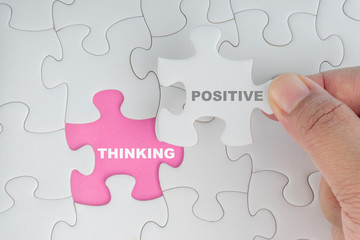 Fototapeta premium Hand holding piece of jigsaw puzzle with word POSITIVE THINKING. Selective focus