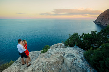 Naklejka premium Couple family traveling together on cliff edge in Norway man and woman lifestyle concept summer vacations outdoor aerial view Lofoten islands Reinebringen mountain top