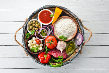 Ingredients for pizza in a wooden box. Top view. On a wooden background. Free copy space.