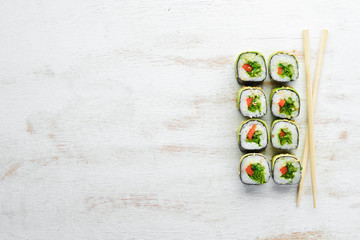 Sushi roll with avocado, cucumber and tomato. Japanese cuisine. Top view. On a white wooden background
