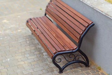 Bench made of wood and metal. Walk around town. Vacation spot. Wooden bench. Paving slab. Metal...