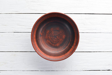 Clay dishes. A plate on a white wooden background. Top view. Free copy space.