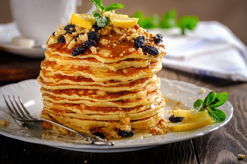 Pancakes with honey, nuts and raisins with a cup of coffee