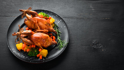 Baked quail. On a black background. Top view. Free space for your text.