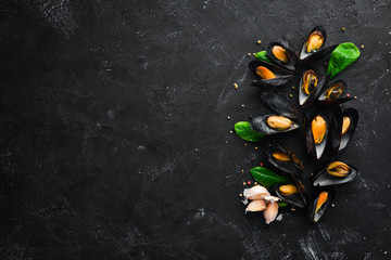 Boiled mussels with spices in a plate. Top view. Free space for your text. On the old background. - obrazy, fototapety, plakaty
