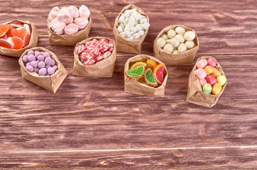 candies, lollipops, caramel, in paper bags on wooden background