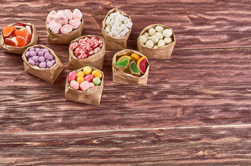 candies, lollipops, caramel, in paper bags on wooden background