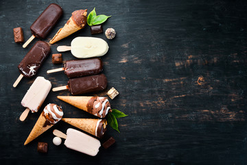 A set of ice cream with chocolate, nuts and jam. On a black background. Top view. Free copy space.
