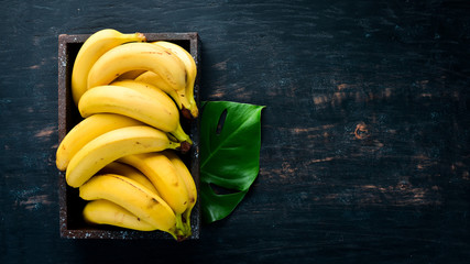 Bananas on a black wooden surface. Tropical Fruits. Top view. Free copy space.