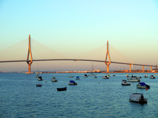 Obraz premium Fishing boats in sunset at the Puente de la Constitución, called La Pepa, in the bay of Cádiz, Andalusia. Spain