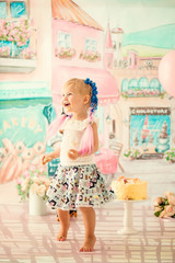 Portrait of a little cheerful birthday girl with the first cake. Eating the first cake. Smash cake.