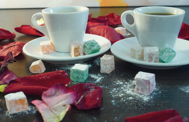 two cups of espresso, close-up, studded with rose petals, with marmalade in powdered sugar