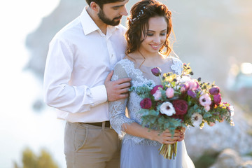 Wedding couple at breathtaking landscape with rock and sea