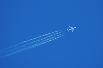 Jet aircraft flying at high altitude with contrails.