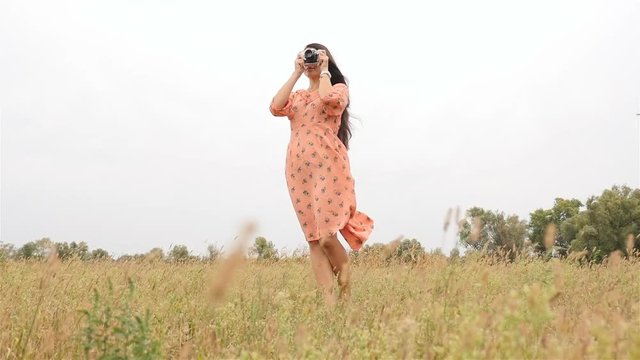 Beautiful girl in a waving dress. Photographing nature. Slow motion. Camera in hand