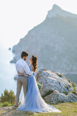 Wedding couple in love kissing and hugging near rocks on beautiful landscape.