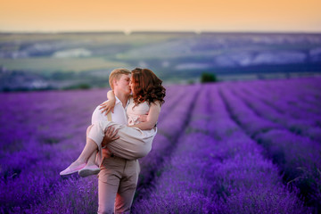 a loving couple standing in a lavender field looking at a pink cloud in the shape of a heart