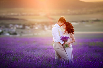 Fototapeta na wymiar a loving couple standing in a lavender field looking at a pink cloud in the shape of a heart