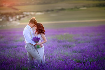 a loving couple standing in a lavender field looking at a pink cloud in the shape of a heart