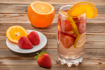Glass of detox water with strawberry and orange on wooden background. Soft focus.