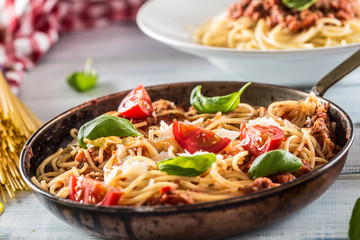 Italian pasta spaghetti bolognese in old pan with tomatoes parmesan cheese and basil