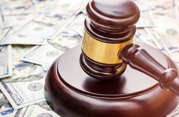 Judge's gavel on background of dollar bills.