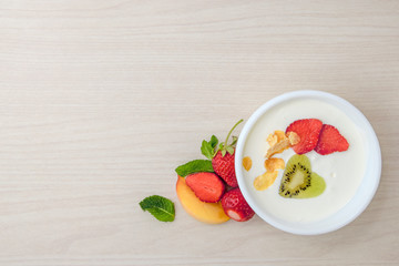 Morning breakfast, yogurt with fruit in a plate on the table, top view