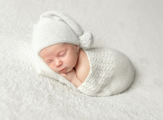 llitle baby in white knitted hat and suit sleeping