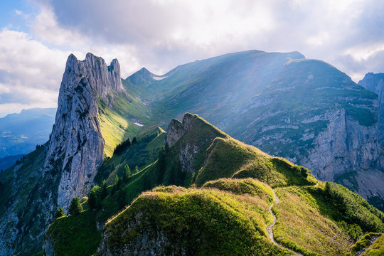Mountain landscape in the Swiss Alps with jagged peaks and a pristine blue mountain lake in the valley far below