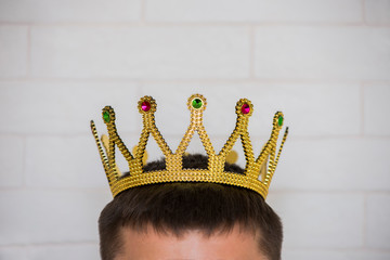The head of a man with a crown on it against a white brick wall