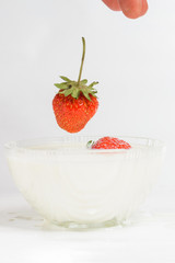 Splashes of milk from falling strawberries, white background.