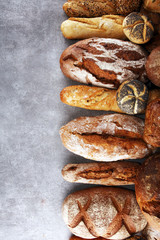 Assortment of baked bread and bread rolls on stone table background