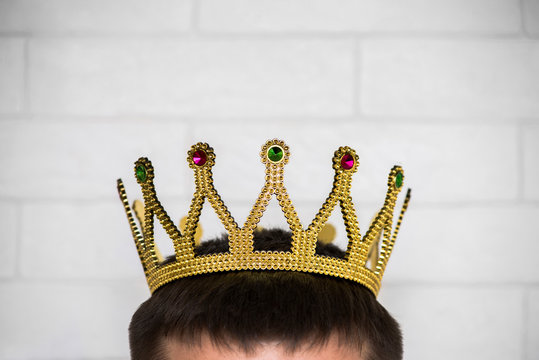 The head of a man with a crown on it against a white brick wall