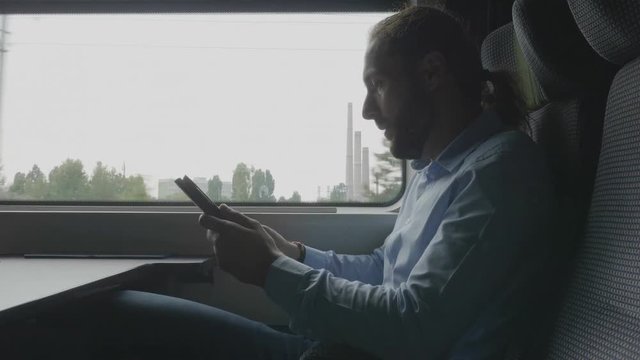 Office millennial male employee traveling by train to work having a video call on digital pc tablet using wireless internet travel and technology concept