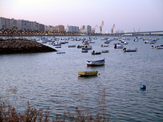 Fototapeta premium Fishing boats in sunset at the Puente de la Constitución, called La Pepa, in the bay of Cádiz, Andalusia. Spain