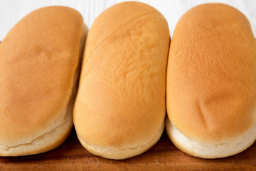 Hot dog buns on wooden board, side view. Close-up.
