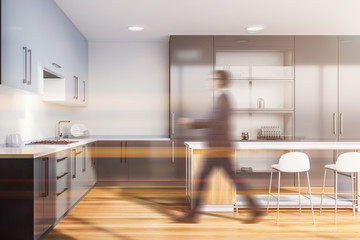 Man in kitchen with gray cupboard and bar