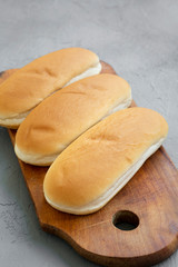 Hot dog buns on rustic wooden board on gray background, low angle view. Close-up.
