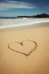 Obraz na płótnie Canvas Romantic vacation on Hawaii concept. Heart drawn on ocean beach sand.