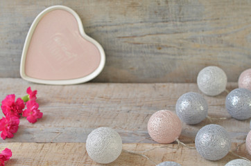 Cotton balls lights on a wooden background. Carnations on a wooden background. A pink heart in the background