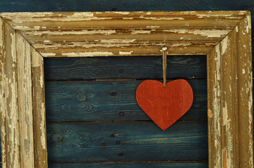 Red wooden heart hanging in a rustic wooden frame