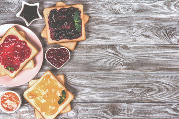Delicious toasts with various sweet jams on grey background. Copyspace for your text, banner.