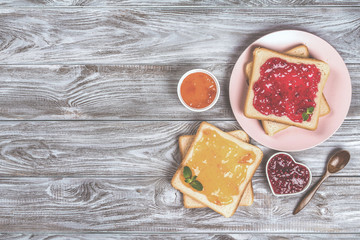 Delicious toasts with various sweet jams on grey background. Copyspace for your text, banner.