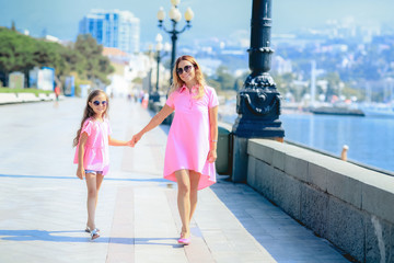 Mom and little charming daughter are walking in the city. Mother  talk to her daughter about bright emotions, they are laughing. Beautiful portrait. Real emotions.