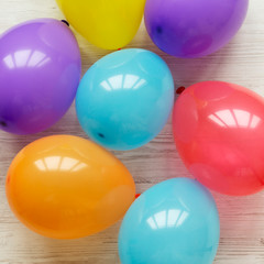 Colorful balloons on white wooden table. Decoration party concept, top view. Flat lay.