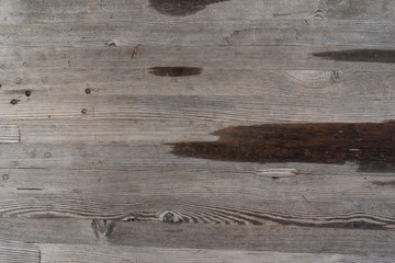 Surface of a heavily weathered wooden bench in the park, with larger water spots