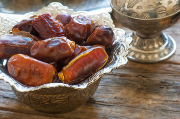 Ramadan palm fruit dates in silver bowl and zam zam water  symbolize sacred month for muslims. Ramadan food and drink fasting break concept